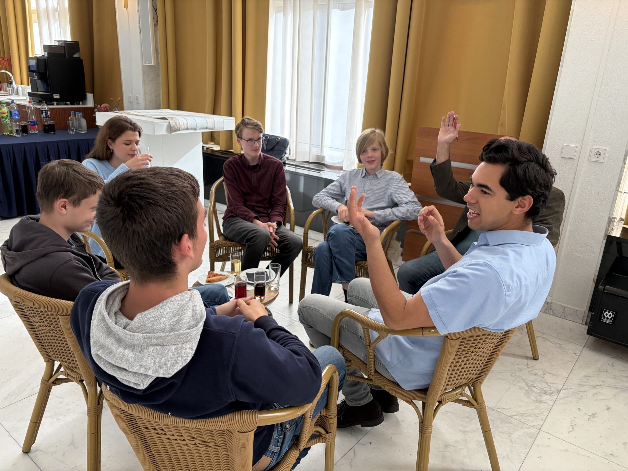 Jongeren onder het genot van een pizzapunt in gesprek met gemeenteraad
